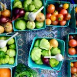 basket of tomato, garlic, and onions on white and blue floral surface