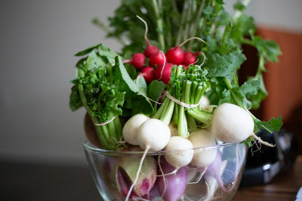 a glass bowl filled with radishes and other vegetables