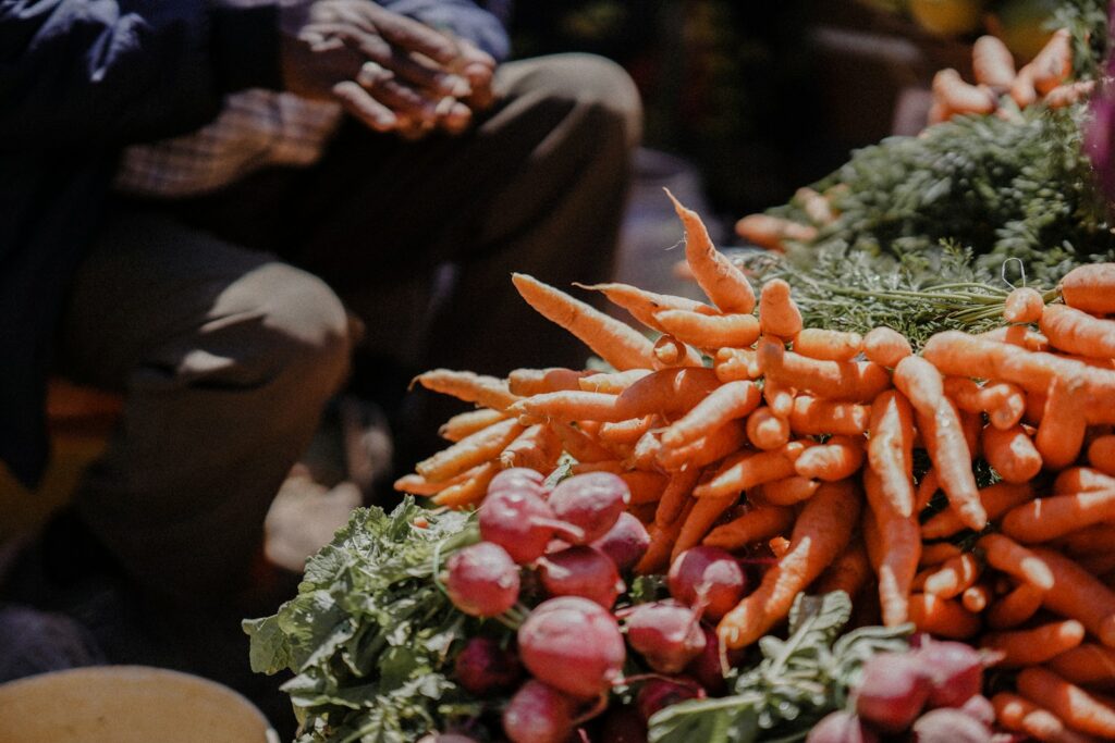 a pile of carrots sitting on top of a pile of lettuce
